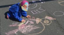 Ein Kind malt mit Kreide Schweinebilder auf den Boden