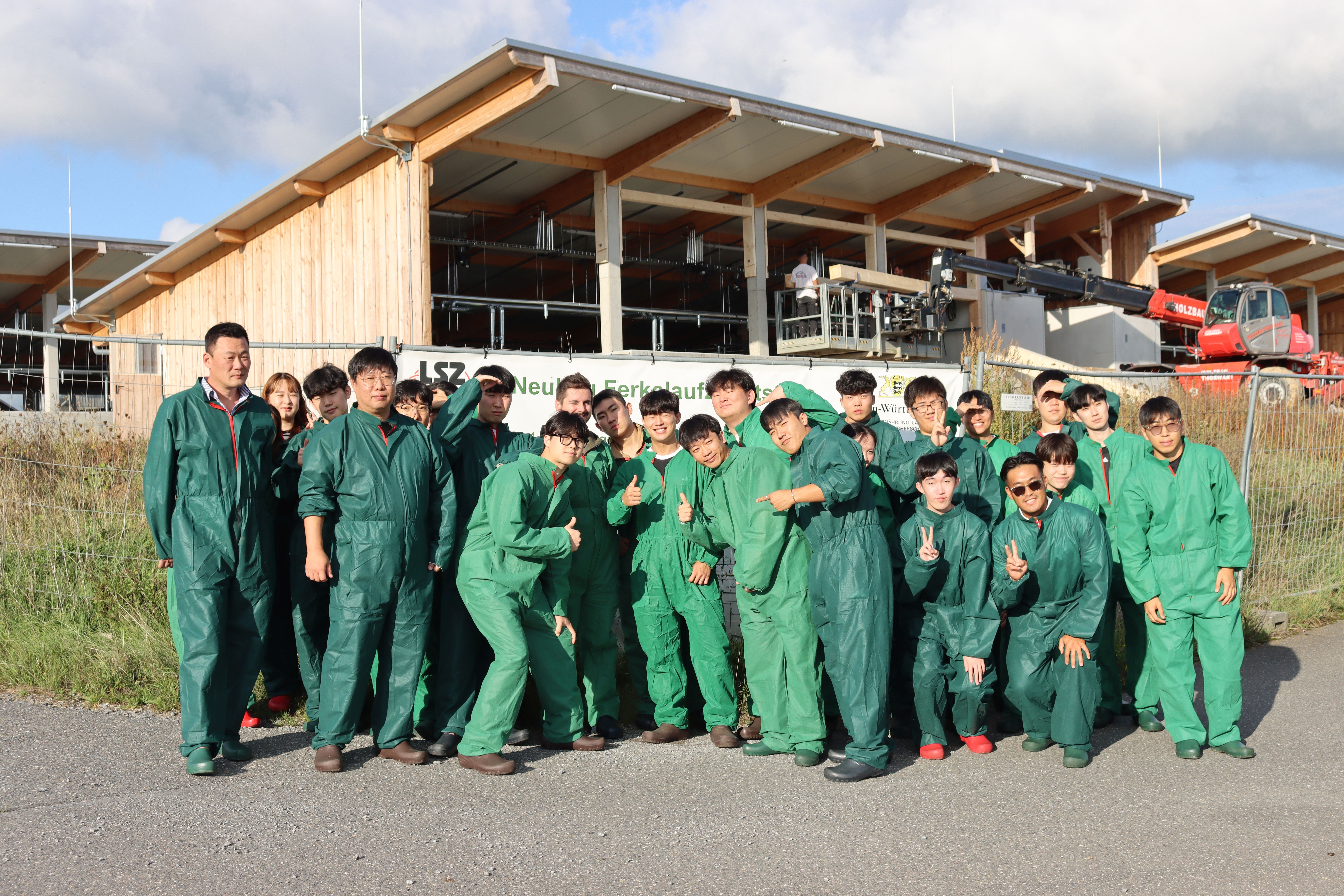 Koreanische Studenten posieren vor dem Stallneubau
