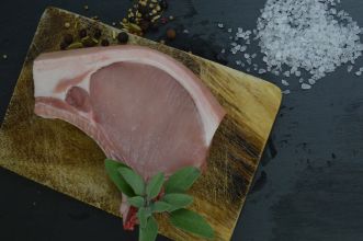 das Bild zeigt ein Schweinekotelett auf einem Brett