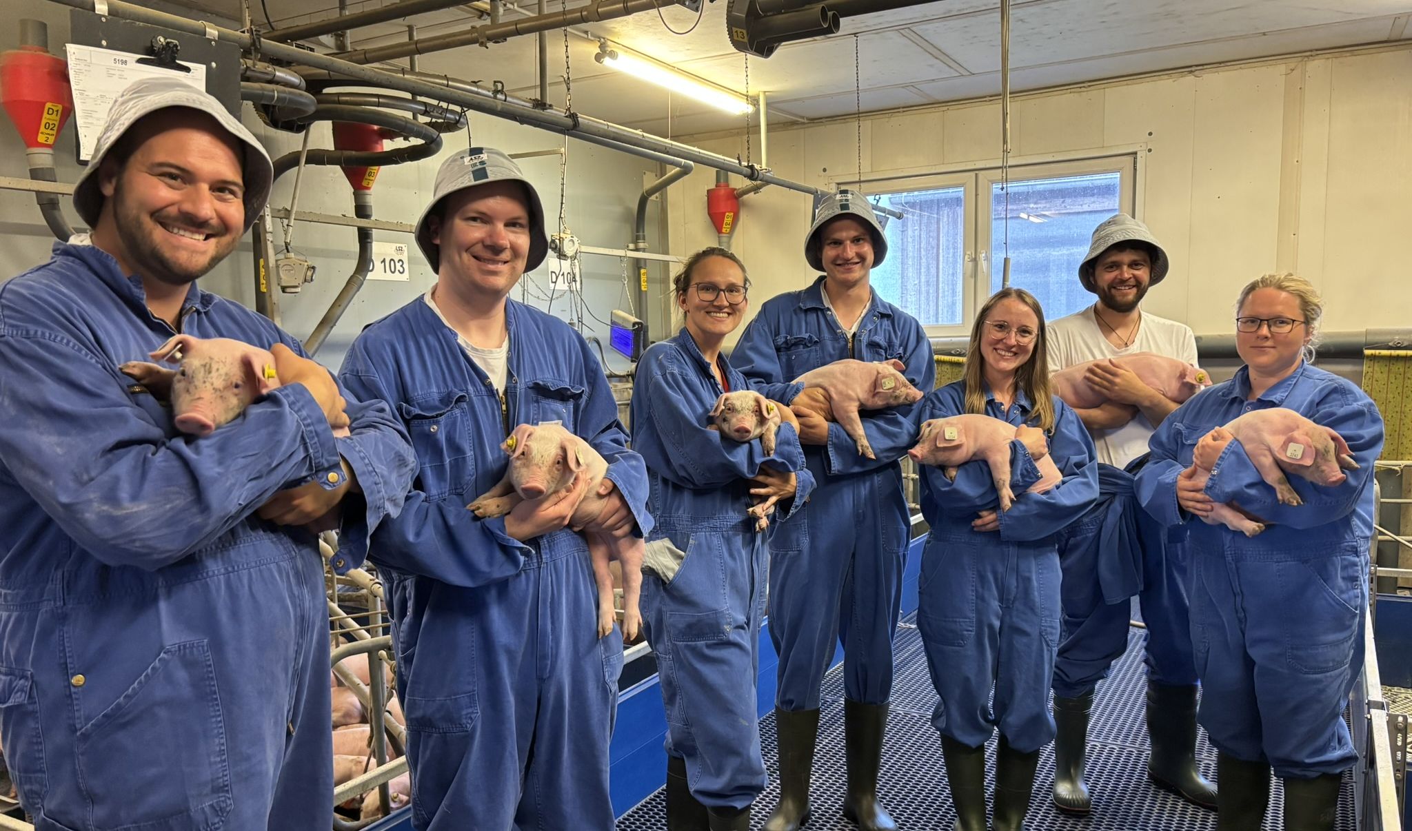 Das Bild zeigt eine Gruppe Referendare, die Ferkel auf dem Arm halten